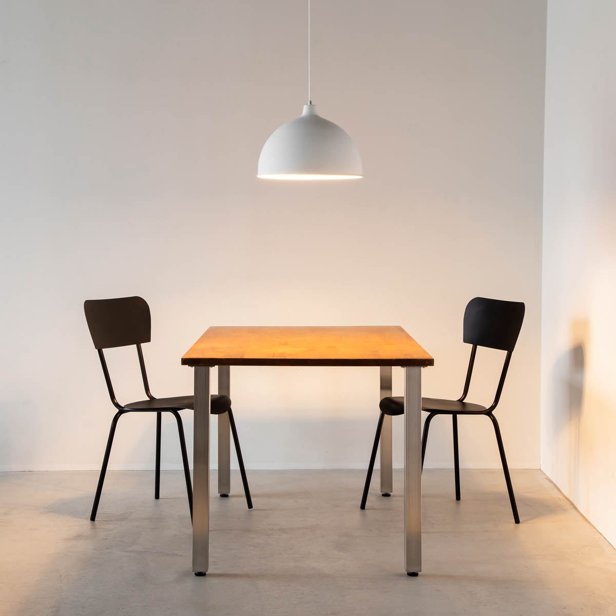 かなでもののマットホワイトの美しいアイアンの質感にシンプルなシェードのデザインが映えるペンダントライトとテーブルと椅子(点灯)