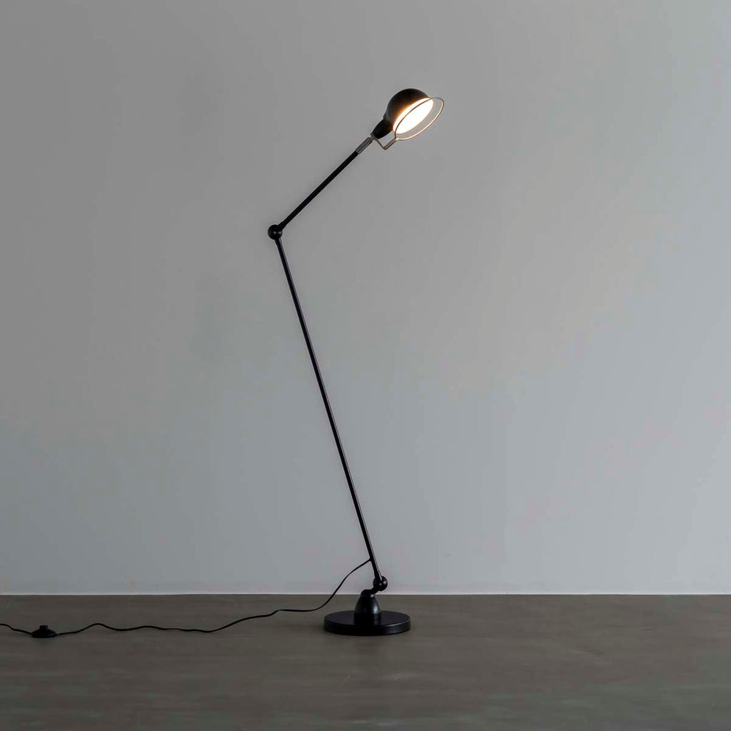 丸みのあるシェードとシャープなシルエットが特徴的なブラックのフロアランプに明かりを灯して