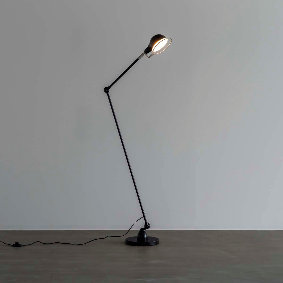 丸みのあるシェードとシャープなシルエットが特徴的なブラックのフロアランプに明かりを灯して