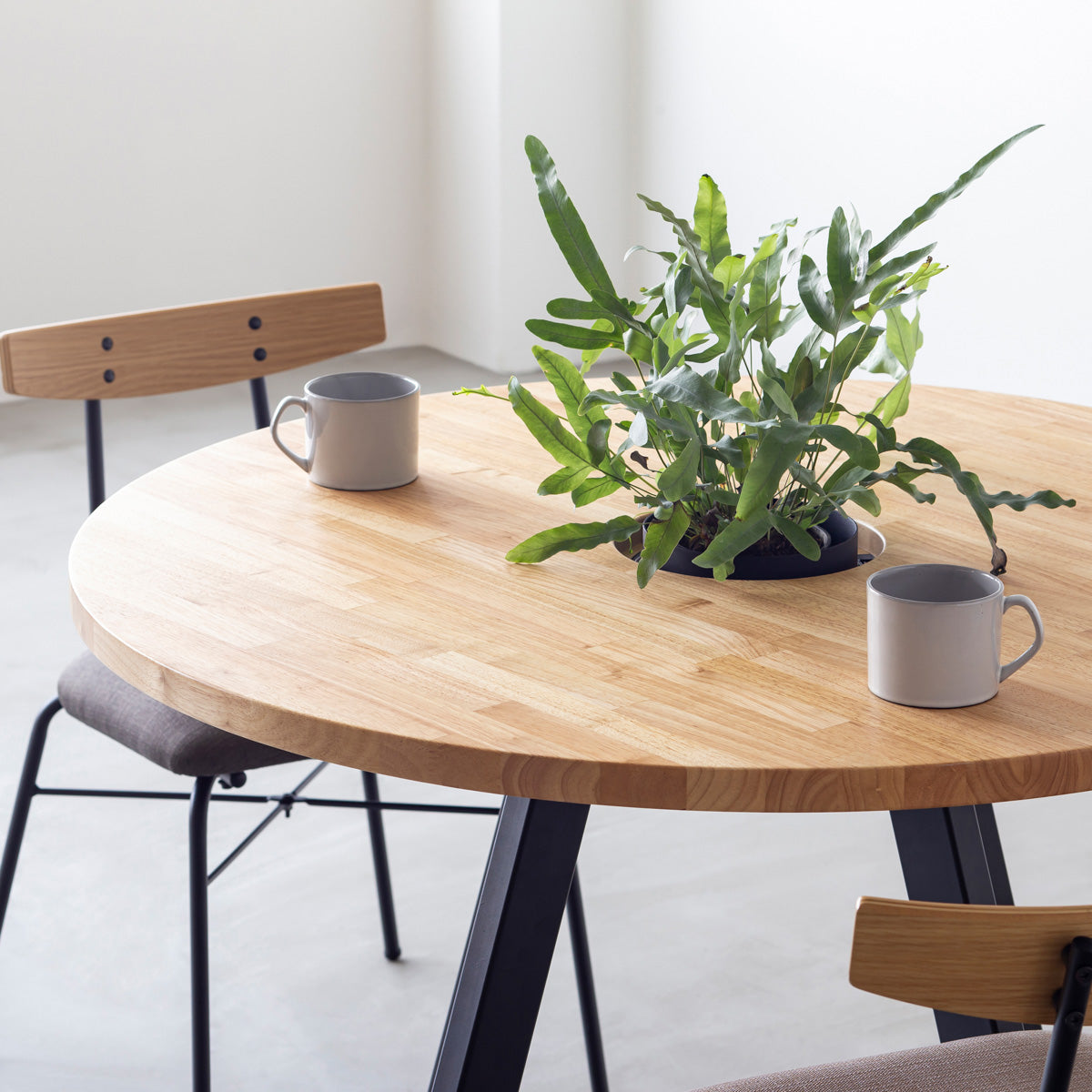 KANADEMONOのワイヤーバスケット付きのラバーウッド材ナチュラルのラウンド天板にマットブラックの4pinアイアン脚を組み合わせたカフェテーブル（使用例2）