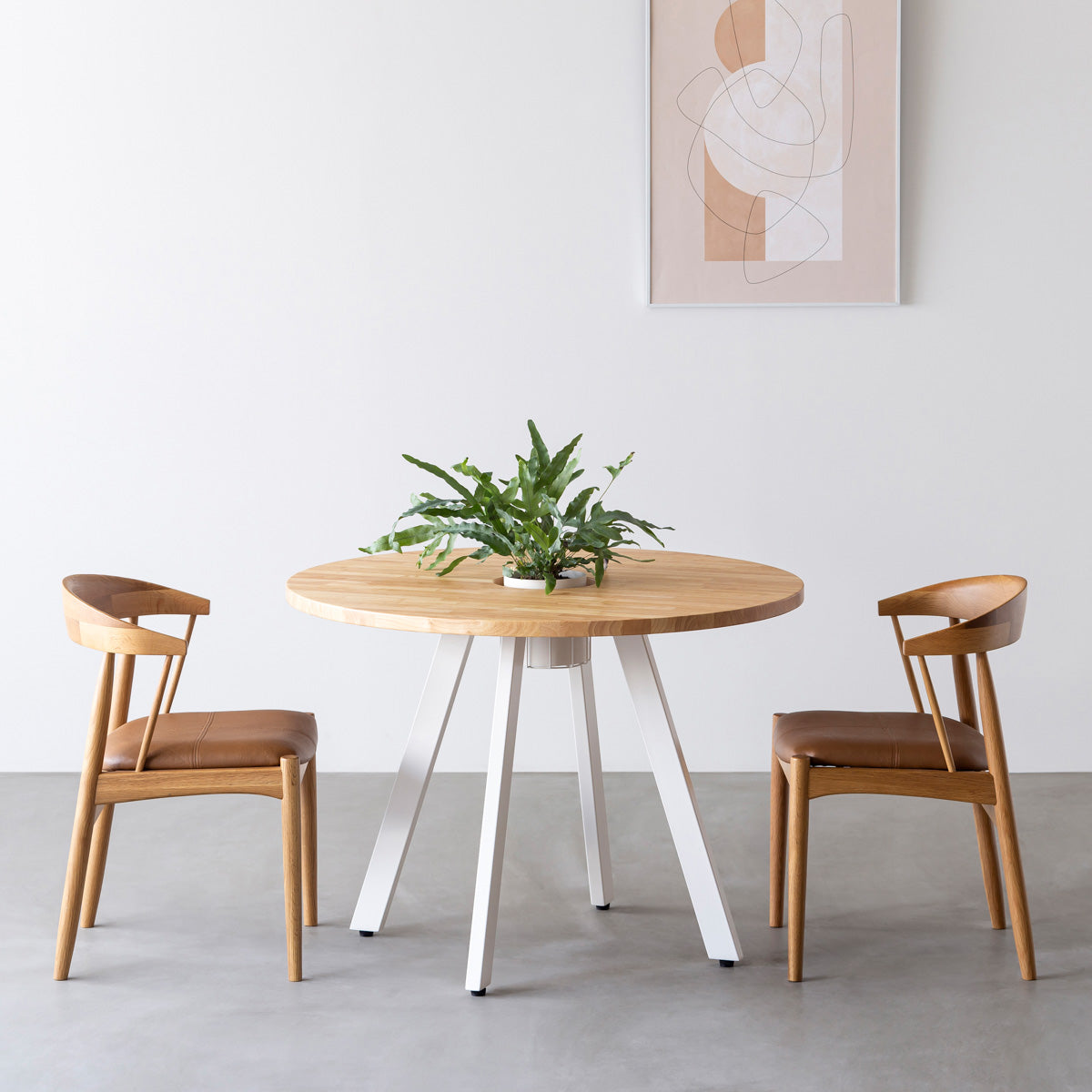 KANADEMONOのワイヤーバスケット付きのラバーウッド材ナチュラルのラウンド天板にマットホワイトの4pinアイアン脚を組み合わせたカフェテーブル（使用例）