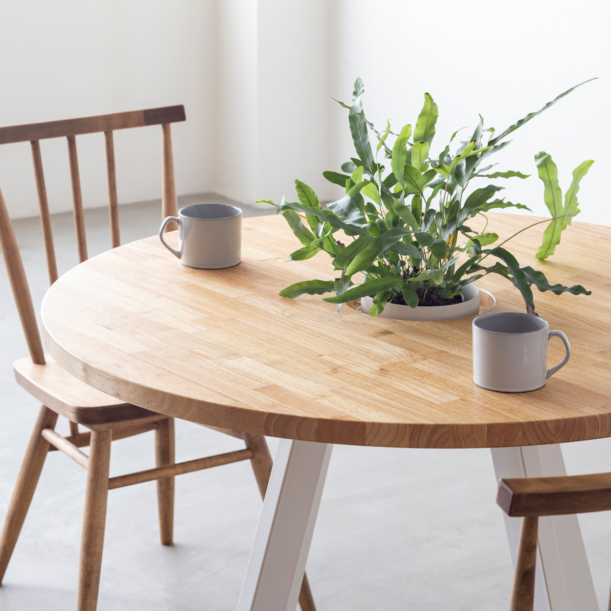 KANADEMONOのワイヤーバスケット付きのラバーウッド材ナチュラルのラウンド天板にマットホワイトの4pinアイアン脚を組み合わせたカフェテーブル（使用例2）