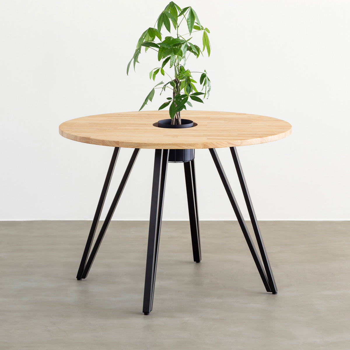 KANADEMONOのワイヤーバスケット付きのラバーウッド材ナチュラルのラウンド天板にマットブラックのトライアングル鉄脚を組み合わせたカフェテーブル（バスケット使用例）