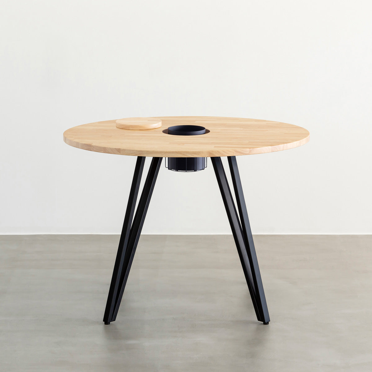 KANADEMONOのワイヤーバスケット付きのラバーウッド材ナチュラルのラウンド天板にマットブラックのトライアングル鉄脚を組み合わせたカフェテーブル（正面）