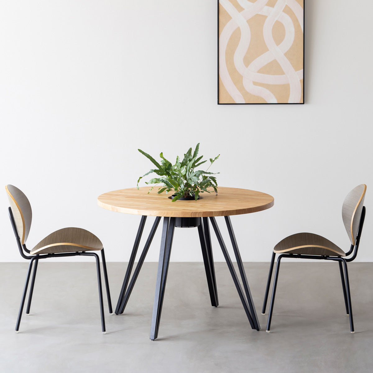 KANADEMONOのワイヤーバスケット付きのラバーウッド材ナチュラルのラウンド天板にマットブラックのトライアングル鉄脚を組み合わせたカフェテーブル（使用例）