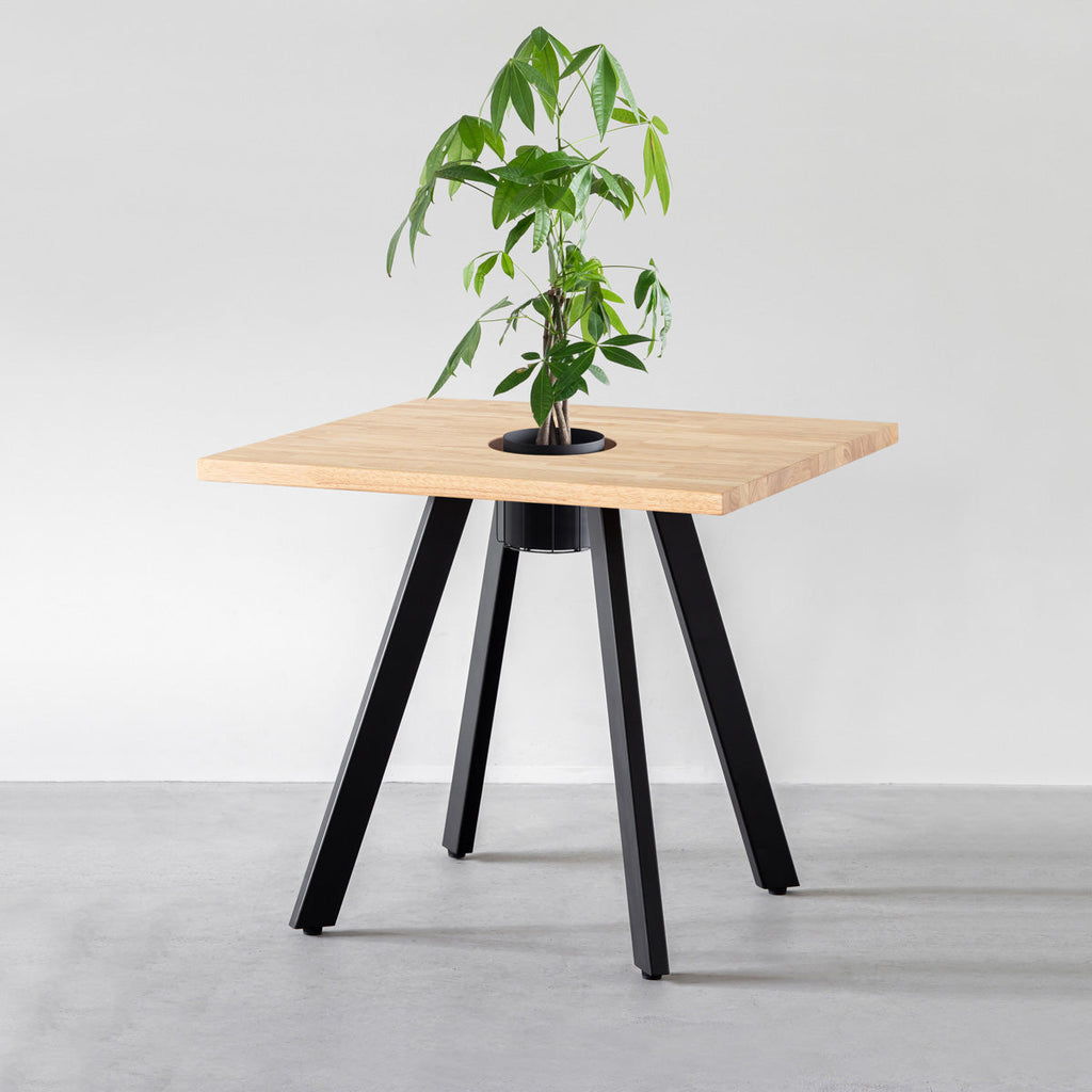 KANADEMONOのワイヤーバスケット付きのスクエアラバーウッド材ナチュラルカラー天板にマットブラックの4pinアイアン脚を組み合わせたカフェテーブル（バスケット使用例）