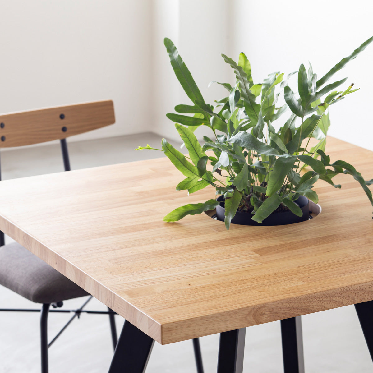 KANADEMONOのワイヤーバスケット付きのスクエアラバーウッド材ナチュラルカラー天板にマットブラックの4pinアイアン脚を組み合わせたカフェテーブル（使用例2）