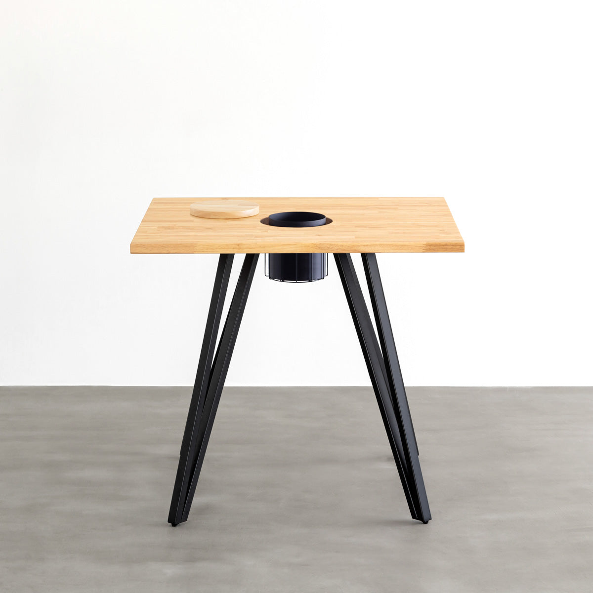 KANADEMONOのワイヤーバスケット付きのラバーウッド材ナチュラルのスクエア天板にマットブラックのトライアングル鉄脚を組み合わせたカフェテーブル（正面）