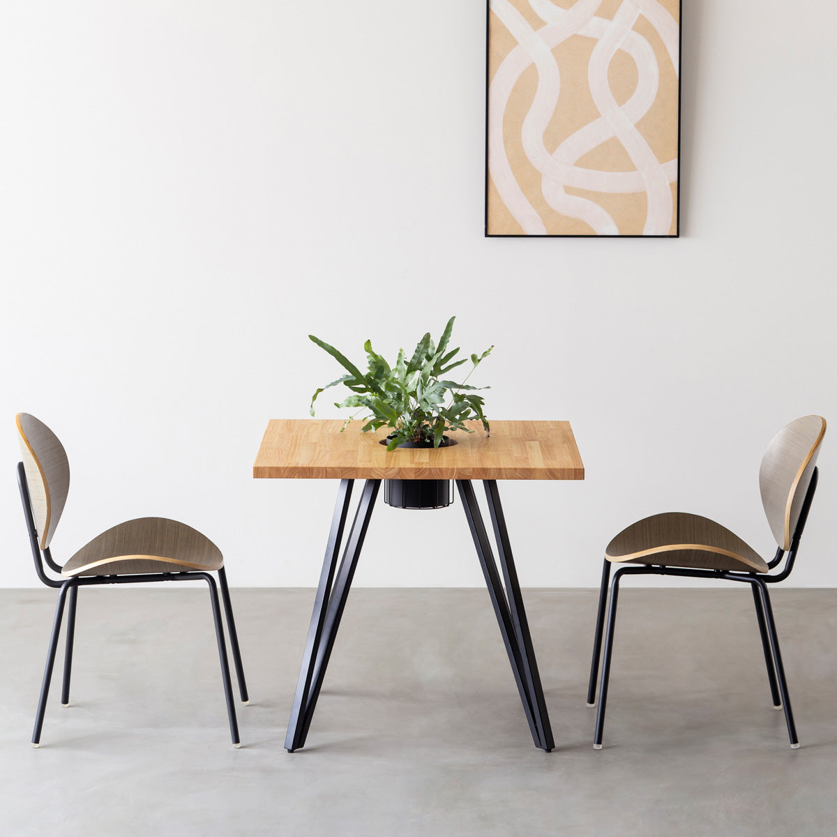 KANADEMONOのワイヤーバスケット付きのラバーウッド材ナチュラルのスクエア天板にマットブラックのトライアングル鉄脚を組み合わせたカフェテーブル（使用例）