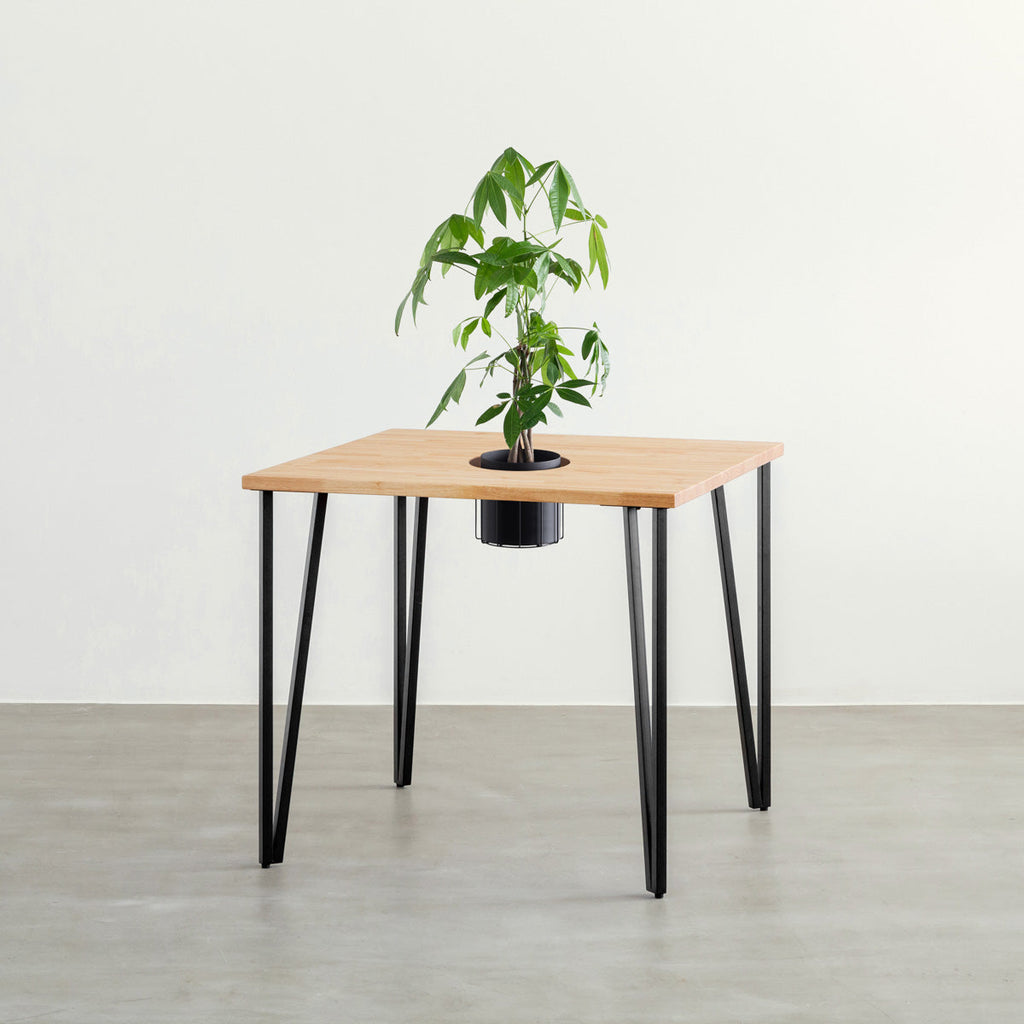 KANADEMONOのワイヤーバスケット付きのラバーウッド材ナチュラルのスクエア天板にマットブラックのトライアングルStraight鉄脚を組み合わせたカフェテーブル（バスケット使用例）