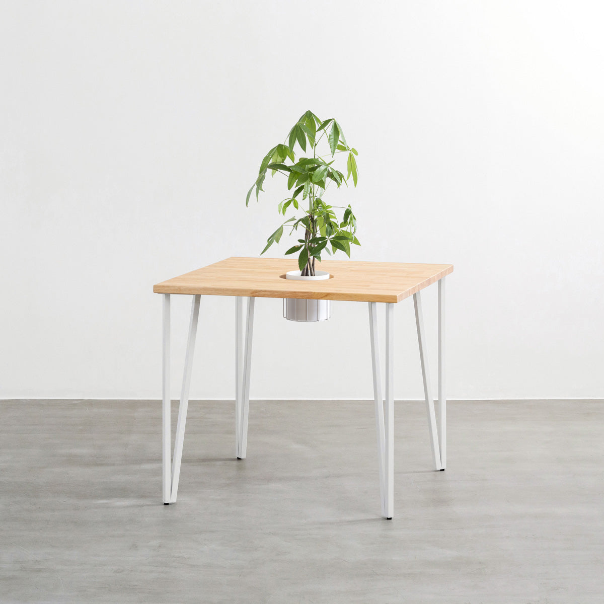 KANADEMONOのワイヤーバスケット付きのラバーウッド材ナチュラルのスクエア天板にマットホワイトのトライアングルStraight鉄脚を組み合わせたカフェテーブル（バスケット使用例）