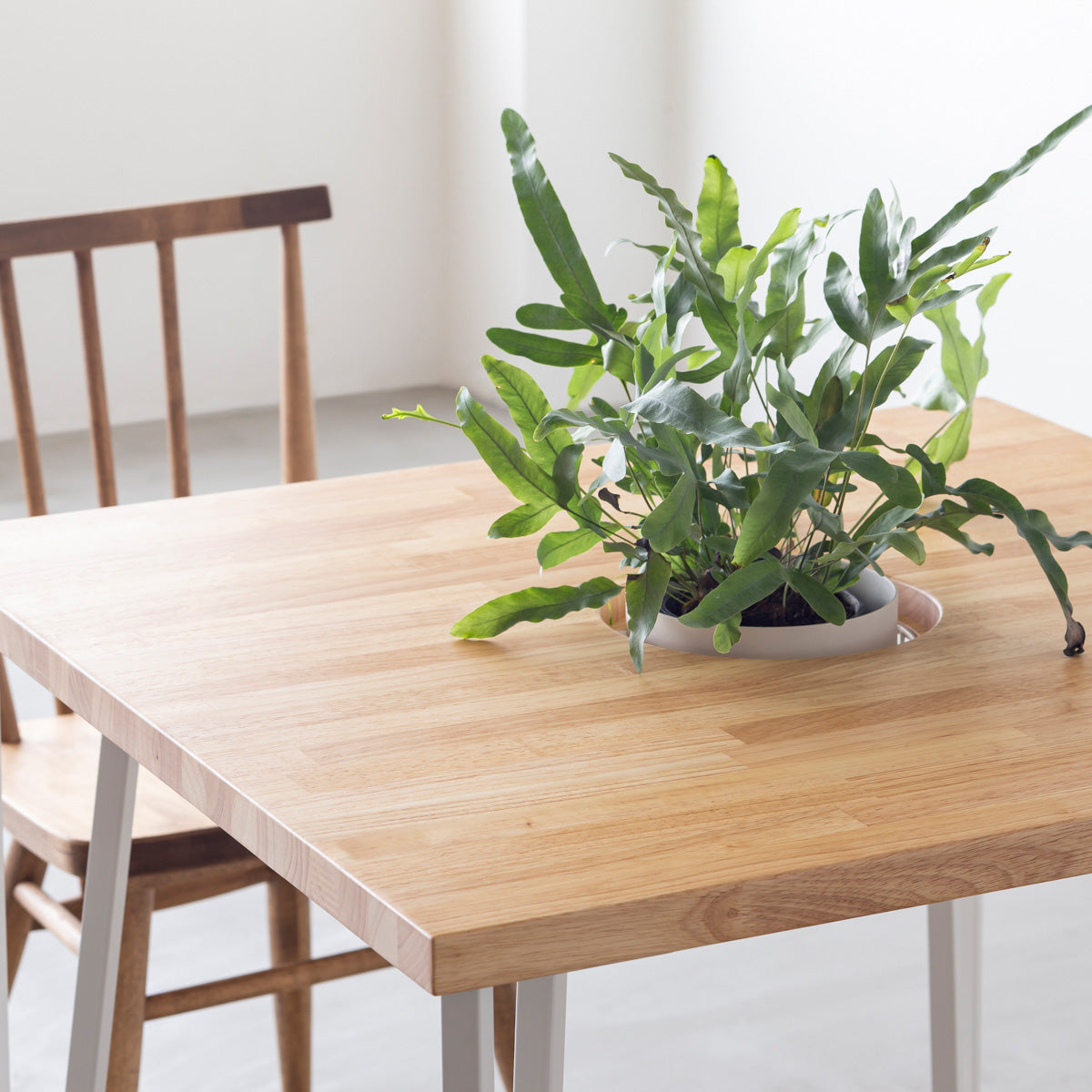 KANADEMONOのワイヤーバスケット付きのラバーウッド材ナチュラルのスクエア天板にマットホワイトのトライアングルStraight鉄脚を組み合わせたカフェテーブル（使用例2）