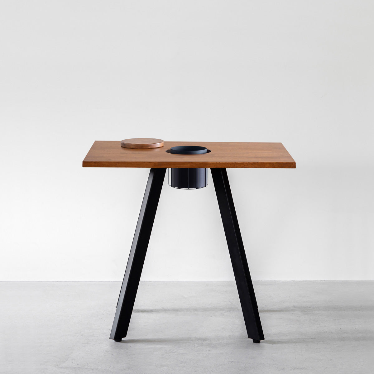 KANADEMONOのワイヤーバスケット付きのスクエアラバーウッド材ブラウンカラー天板にマットブラックの4pinアイアン脚を組み合わせたカフェテーブル（正面）