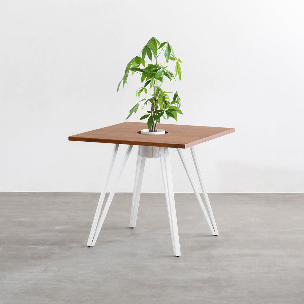 KANADEMONOのワイヤーバスケット付きのラバーウッド材ブラウンのスクエア天板にマットホワイトのトライアングル鉄脚を組み合わせたカフェテーブル（バスケット使用例）