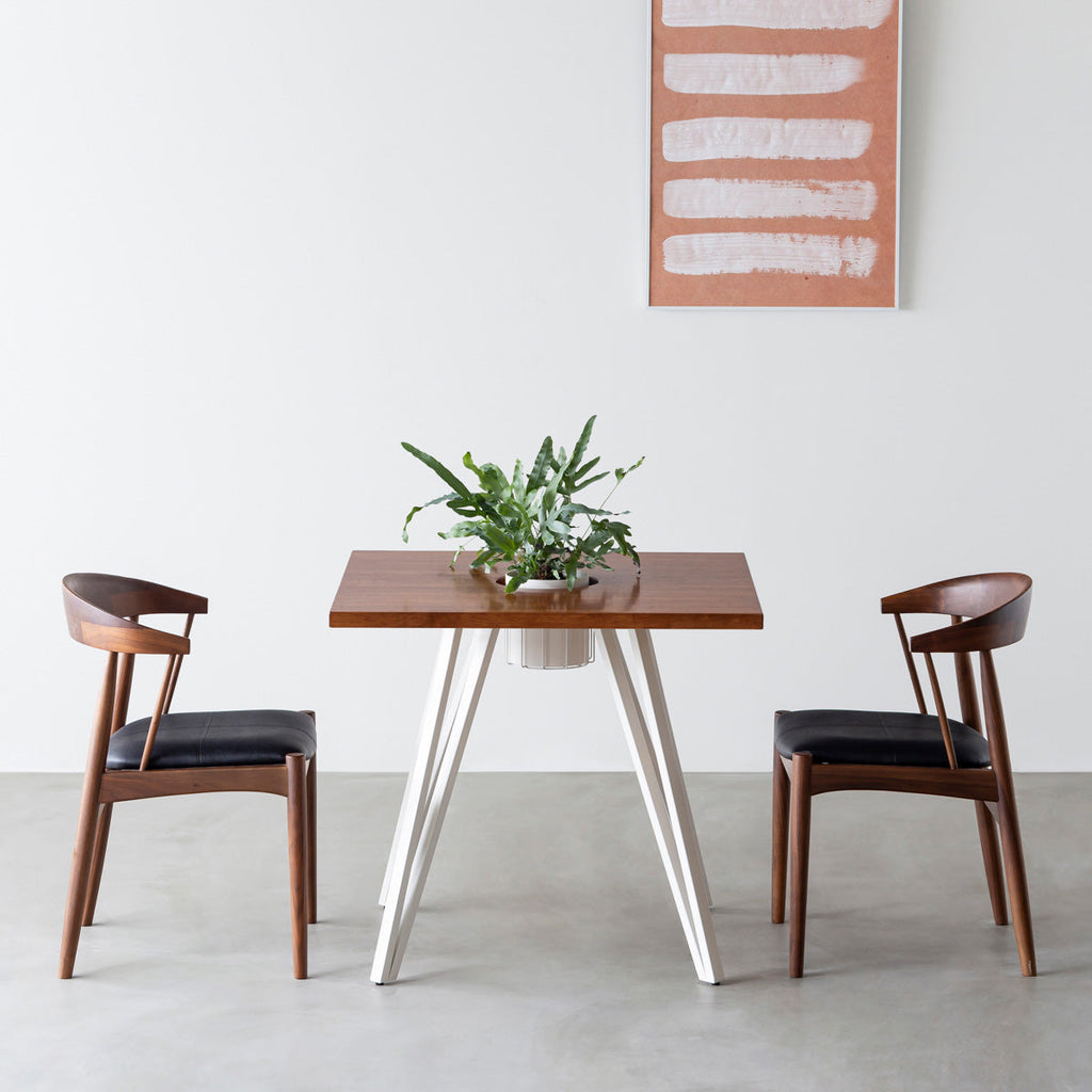 KANADEMONOのワイヤーバスケット付きのラバーウッド材ブラウンのスクエア天板にマットホワイトのトライアングル鉄脚を組み合わせたカフェテーブル（使用例）