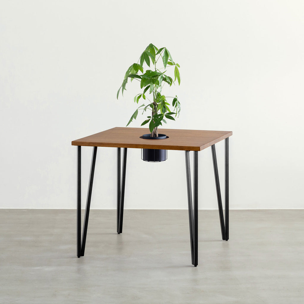 KANADEMONOのワイヤーバスケット付きのラバーウッド材ブラウンのスクエア天板にマットブラックのトライアングルStraight鉄脚を組み合わせたカフェテーブル（バスケット使用例）