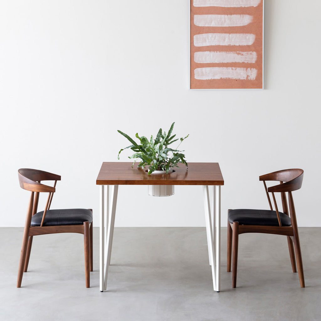 KANADEMONOのワイヤーバスケット付きのラバーウッド材ブラウンのスクエア天板にマットホワイトのトライアングルStraight鉄脚を組み合わせたカフェテーブル（使用例）