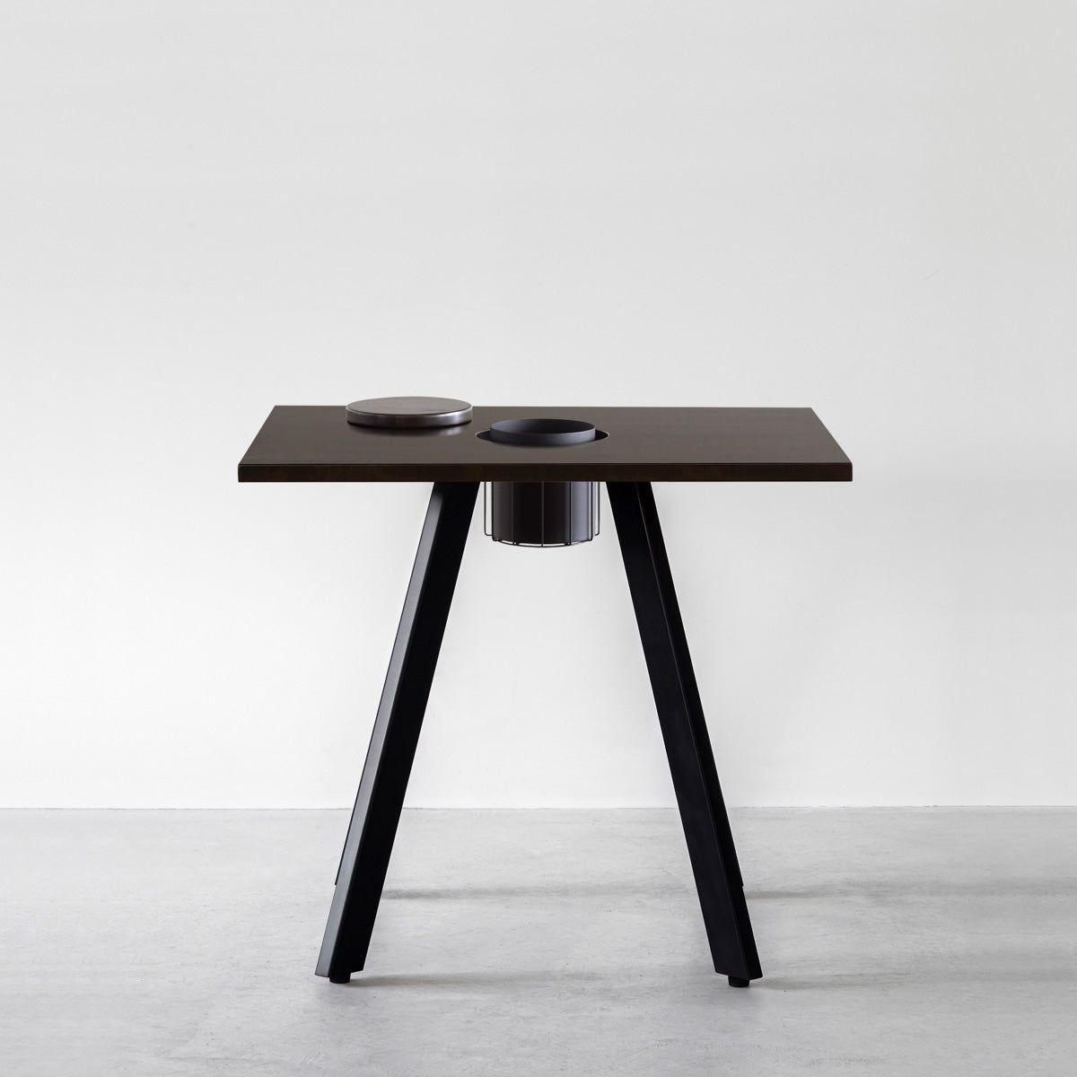 KANADEMONOのワイヤーバスケット付きのスクエアラバーウッド材ブラックブラウンカラー天板にマットブラックの4pinアイアン脚を組み合わせたカフェテーブル（正面）