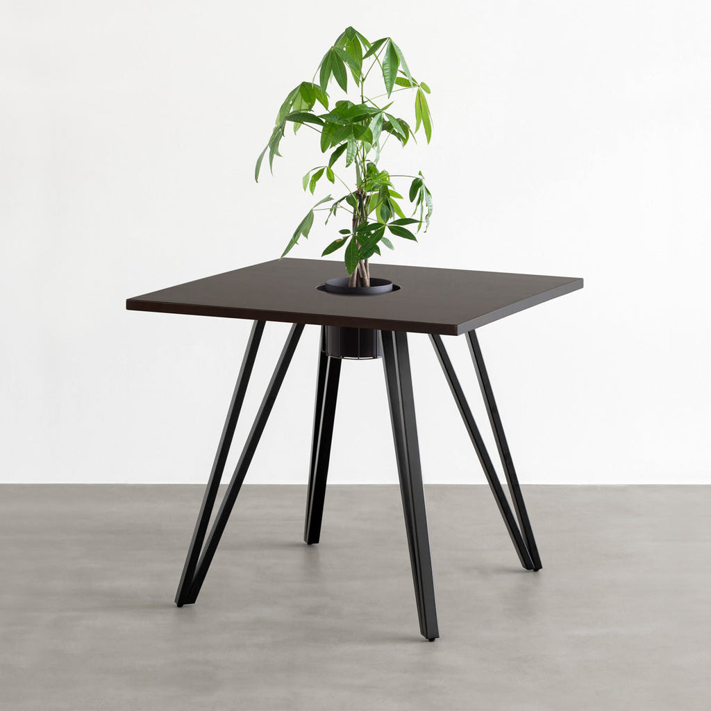 KANADEMONOのワイヤーバスケット付きのラバーウッド材ブラックブラウンのスクエア天板にマットブラックのトライアングル鉄脚を組み合わせたカフェテーブル（バスケット使用例）