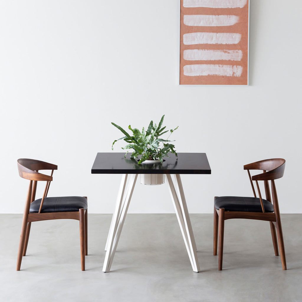 KANADEMONOのワイヤーバスケット付きのラバーウッド材ブラックブラウンのスクエア天板にマットホワイトのトライアングル鉄脚を組み合わせたカフェテーブル（使用例）