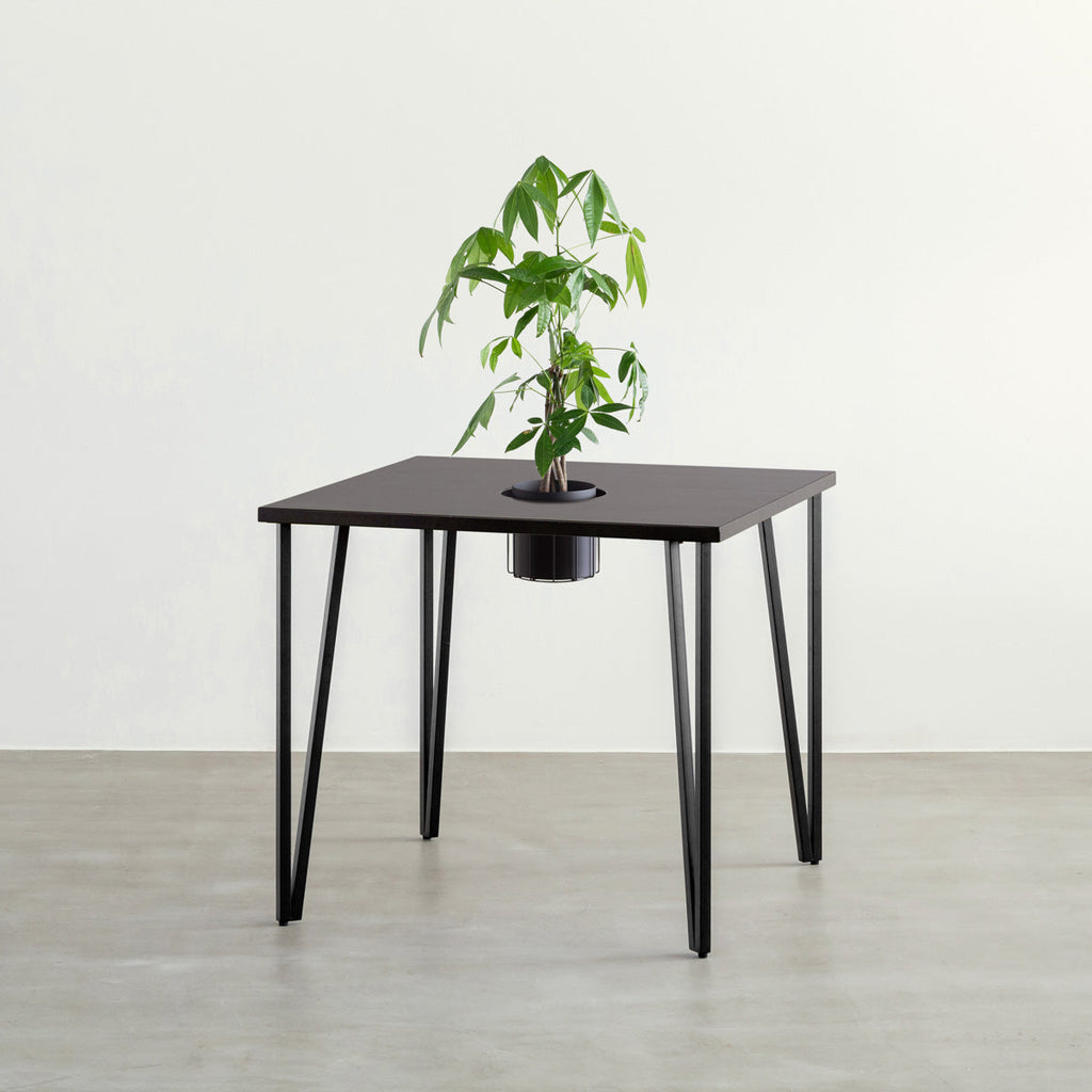 KANADEMONOのワイヤーバスケット付きのラバーウッド材ブラックブラウンのスクエア天板にマットブラックのトライアングルStraight鉄脚を組み合わせたカフェテーブル（バスケット使用例）