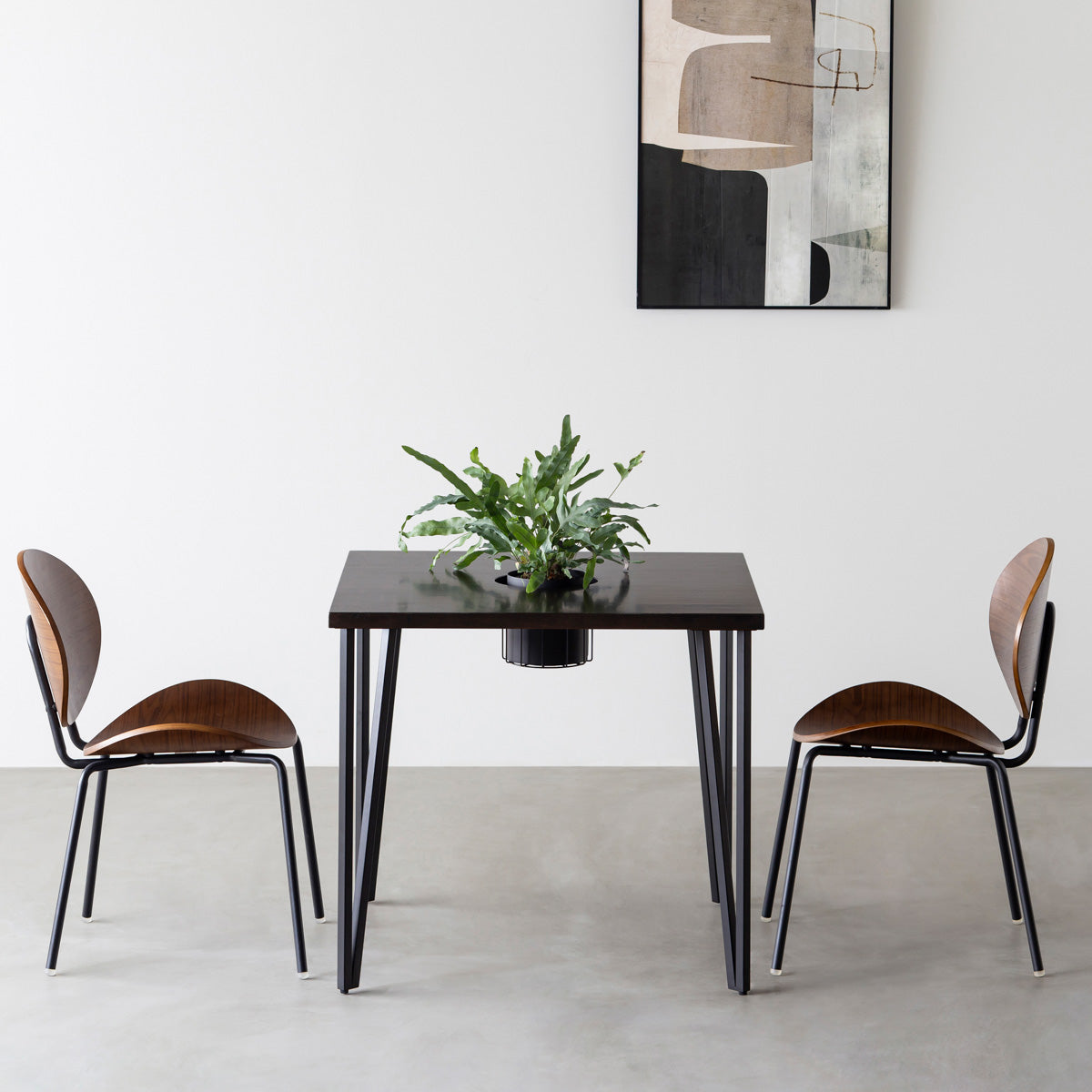 KANADEMONOのワイヤーバスケット付きのラバーウッド材ブラックブラウンのスクエア天板にマットブラックのトライアングルStraight鉄脚を組み合わせたカフェテーブル（使用例）