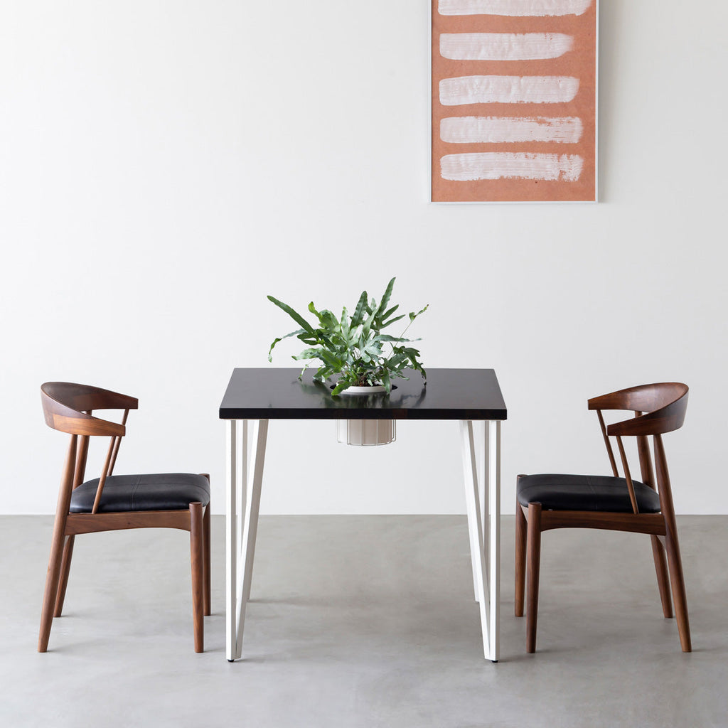 KANADEMONOのワイヤーバスケット付きのラバーウッド材ブラックブラウンのスクエア天板にマットホワイトのトライアングルStraight鉄脚を組み合わせたカフェテーブル（使用例）