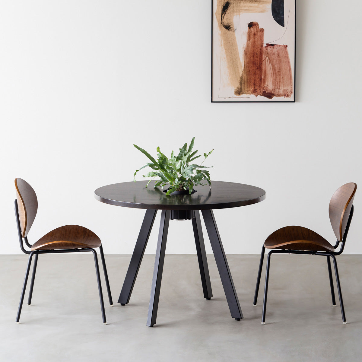 KANADEMONOのワイヤーバスケット付きのラバーウッド材ブラックブラウンのラウンド天板にマットブラックの4pinアイアン脚を組み合わせたカフェテーブル（使用例）