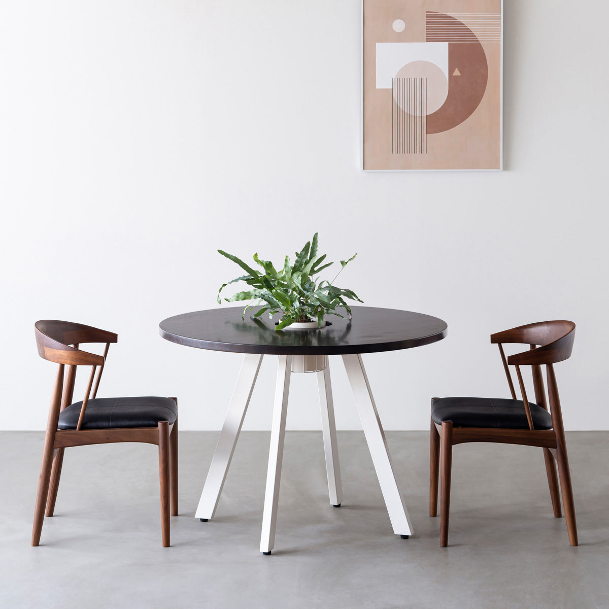 KANADEMONOのワイヤーバスケット付きのラバーウッド材ブラックブラウンのラウンド天板にマットホワイトの4pinアイアン脚を組み合わせたカフェテーブル（使用例）