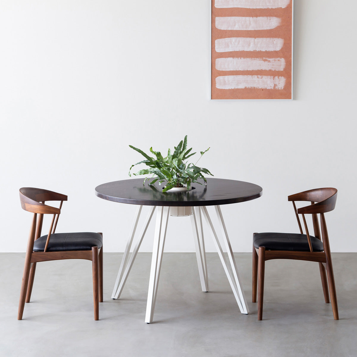 KANADEMONOのワイヤーバスケット付きのラバーウッド材ブラックブラウンのラウンド天板にマットホワイトのトライアングル鉄脚を組み合わせたカフェテーブル（使用例）