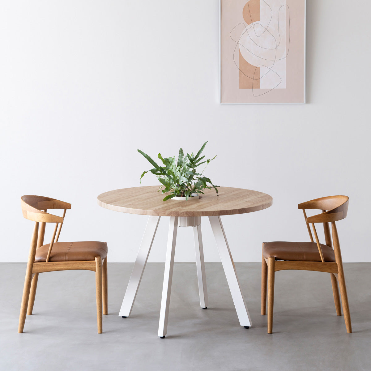 KANADEMONOのワイヤーバスケット付きのラバーウッド材アッシュグレーのラウンド天板にマットホワイトの4pinアイアン脚を組み合わせたカフェテーブル（使用例）