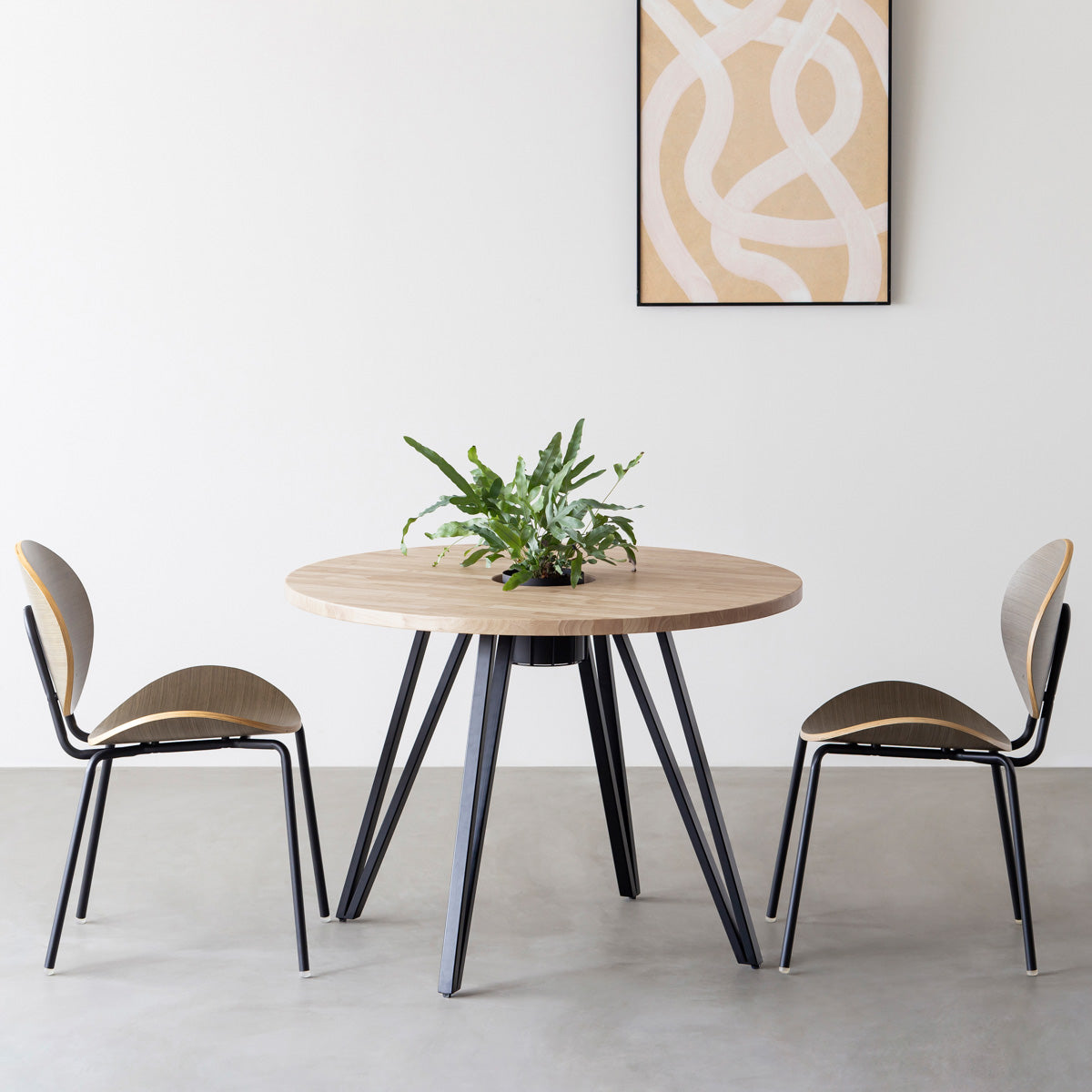 KANADEMONOのワイヤーバスケット付きのラバーウッド材アッシュグレーのラウンド天板にマットブラックのトライアングル鉄脚を組み合わせたカフェテーブル（使用例）