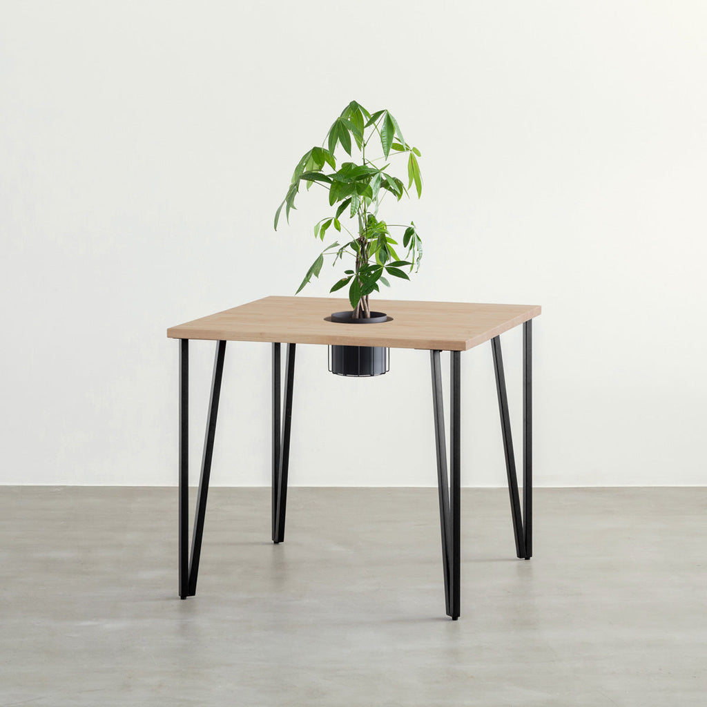 KANADEMONOのワイヤーバスケット付きのラバーウッド材アッシュグレーのスクエア天板にマットブラックのトライアングルStraight鉄脚を組み合わせたカフェテーブル（バスケット使用例）