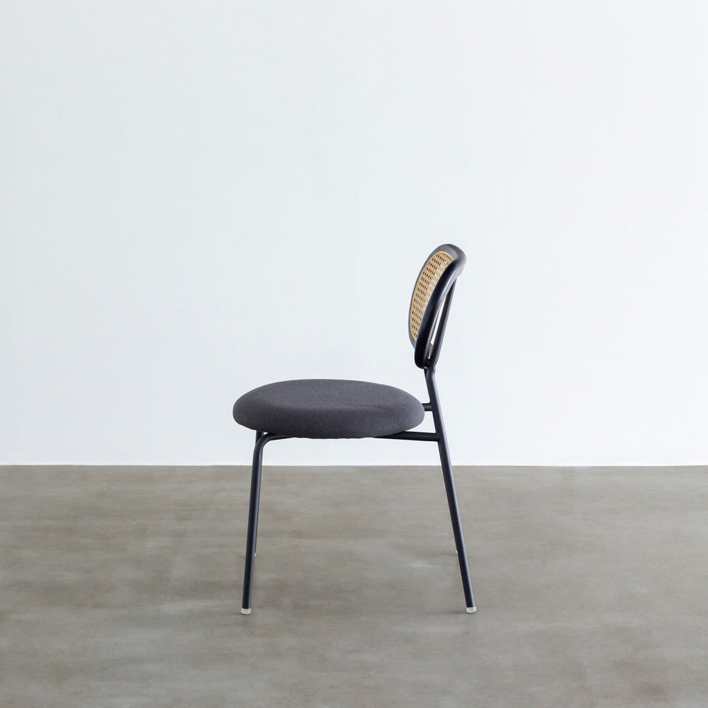 KANADEMONOのラタン調の楕円形の背もたれ、ダークグレーのファブリック座面、ブラックスチール脚が特徴のモダンなダイニングチェア（側面）