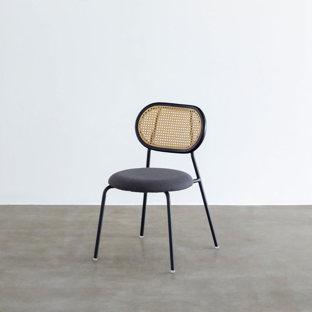 KANADEMONOのラタン調の楕円形の背もたれ、ダークグレーのファブリック座面、ブラックスチール脚が特徴のモダンなダイニングチェア