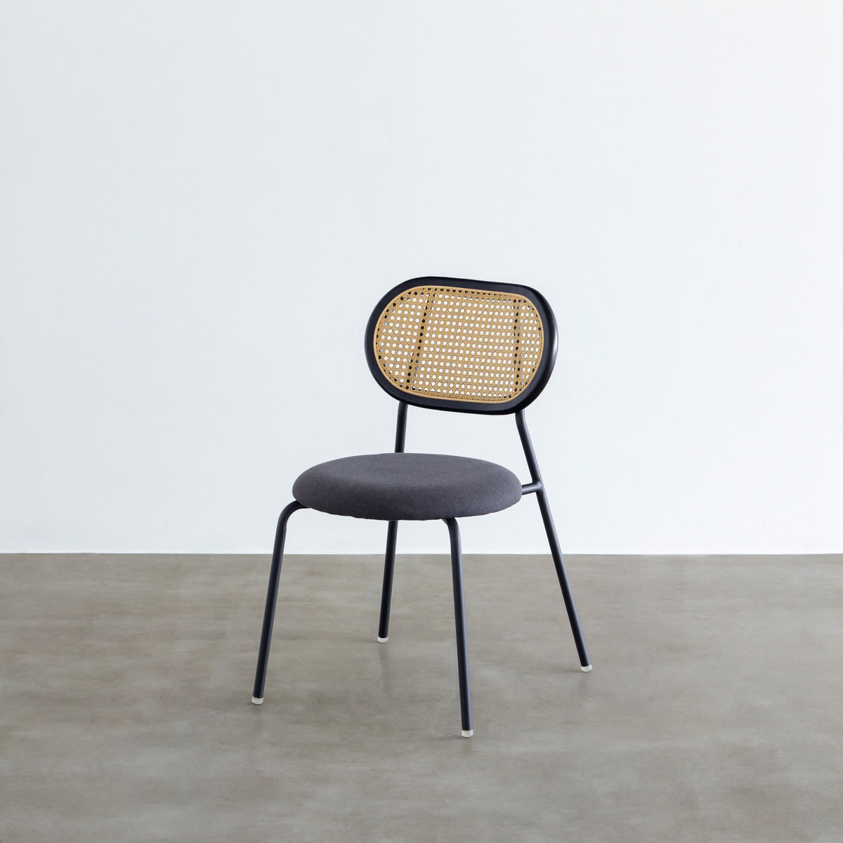 KANADEMONOのラタン調の楕円形の背もたれ、ダークグレーのファブリック座面、ブラックスチール脚が特徴のモダンなダイニングチェア