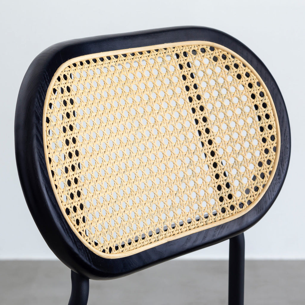 KANADEMONOのラタン調の楕円形の背もたれ、ダークグレーのファブリック座面、ブラックスチール脚が特徴のモダンなダイニングチェア（背もたれ）