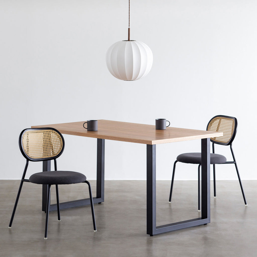 KANADEMONOのラタン調の楕円形の背もたれ、ダークグレーのファブリック座面、ブラックスチール脚が特徴のモダンなダイニングチェア（使用例2）