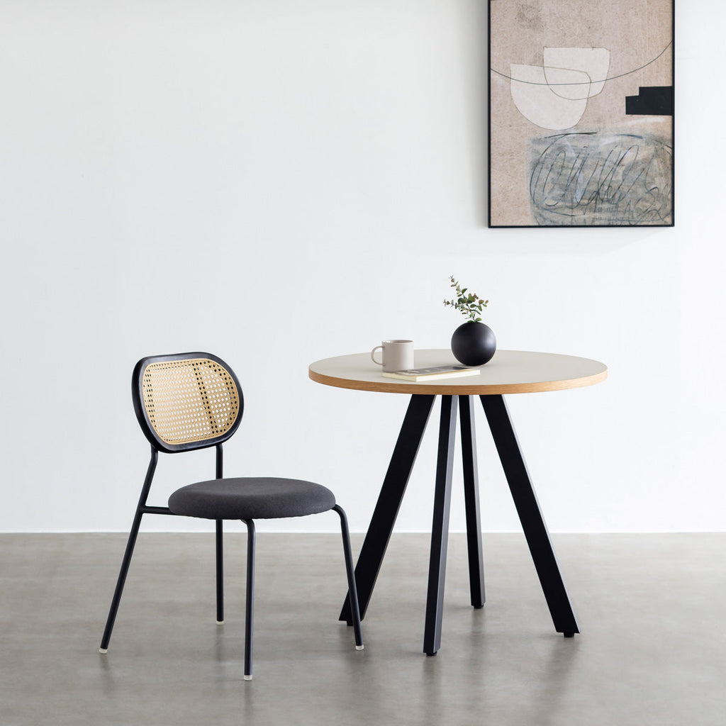 KANADEMONOのラタン調の楕円形の背もたれ、ダークグレーのファブリック座面、ブラックスチール脚が特徴のモダンなダイニングチェア（使用例）