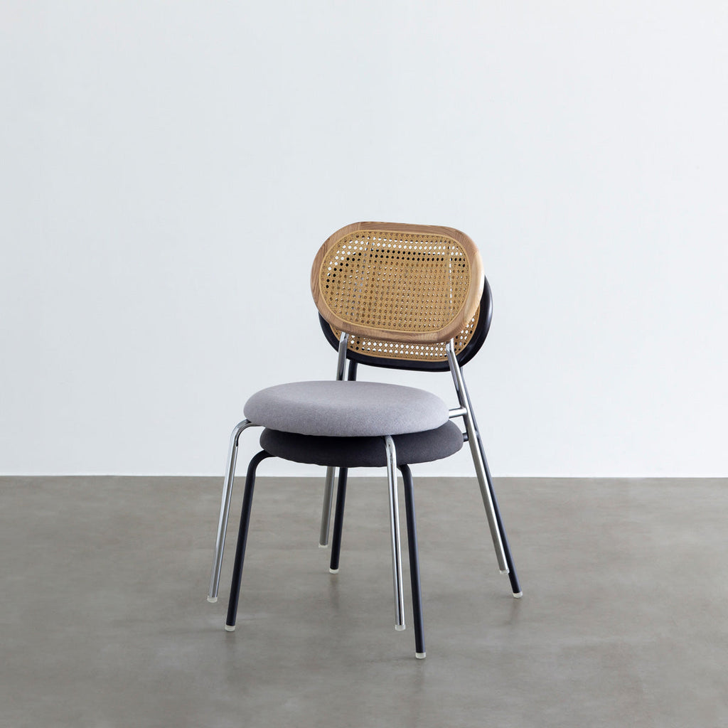 KANADEMONOのラタン調の楕円形の背もたれ、ダークグレーのファブリック座面、ブラックスチール脚が特徴のモダンなダイニングチェア（スタッキング）