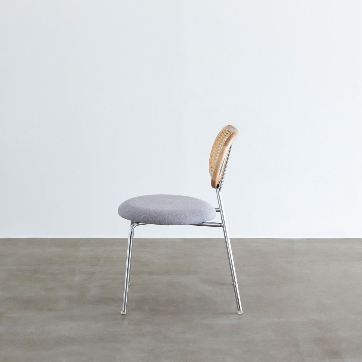 KANADEMONOのラタン調の楕円形の背もたれ、ライトグレーのファブリック座面、シルバースチール脚が特徴のモダンなダイニングチェア（側面）