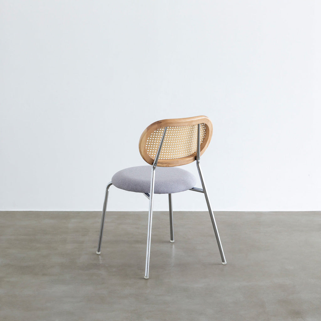 KANADEMONOのラタン調の楕円形の背もたれ、ライトグレーのファブリック座面、シルバースチール脚が特徴のモダンなダイニングチェア（背面）