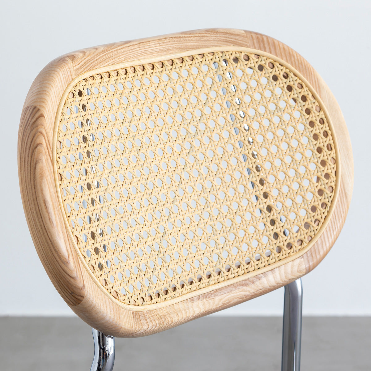 KANADEMONOのラタン調の楕円形の背もたれ、ライトグレーのファブリック座面、シルバースチール脚が特徴のモダンなダイニングチェア（背もたれ）