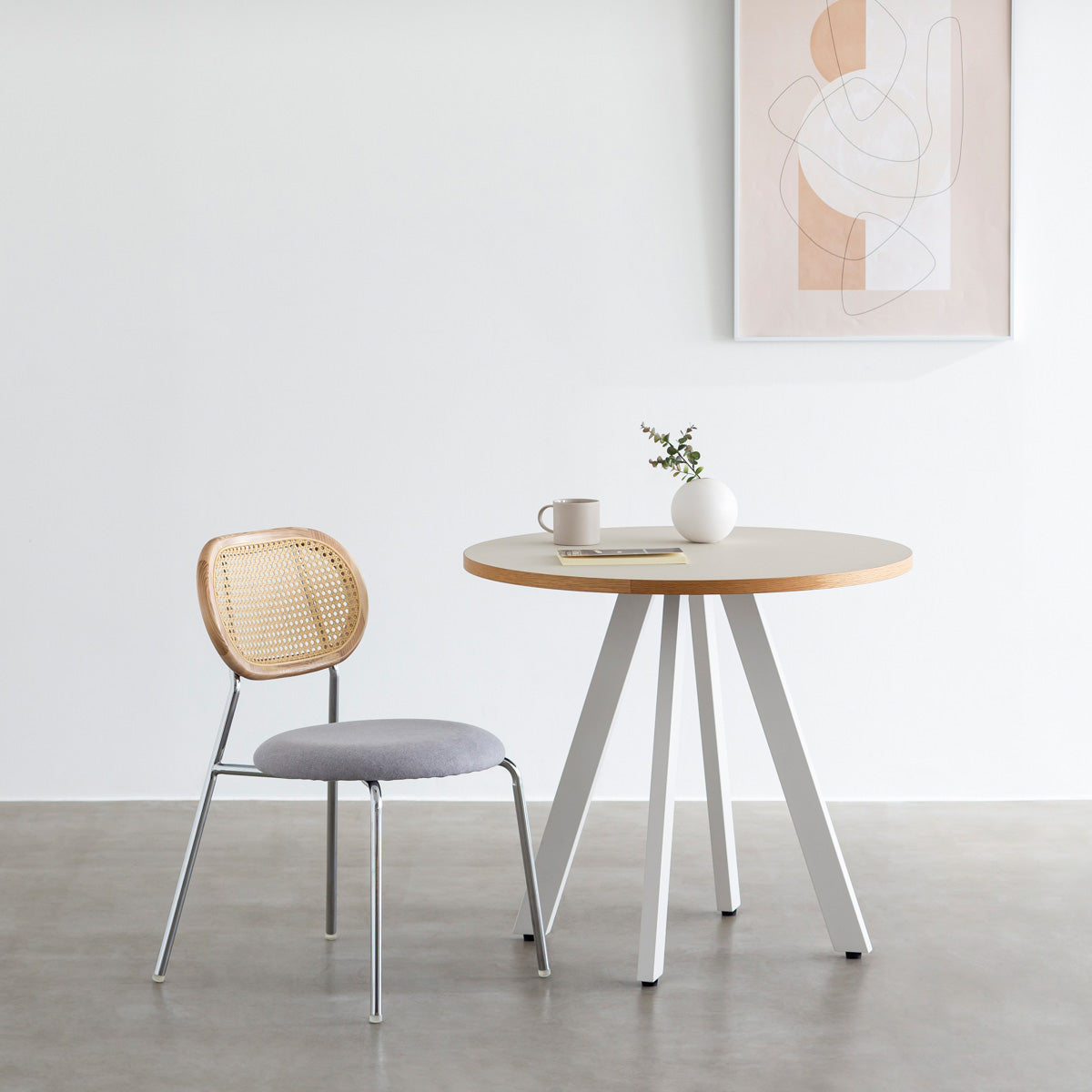 KANADEMONOのラタン調の楕円形の背もたれ、ライトグレーのファブリック座面、シルバースチール脚が特徴のモダンなダイニングチェア（使用例）