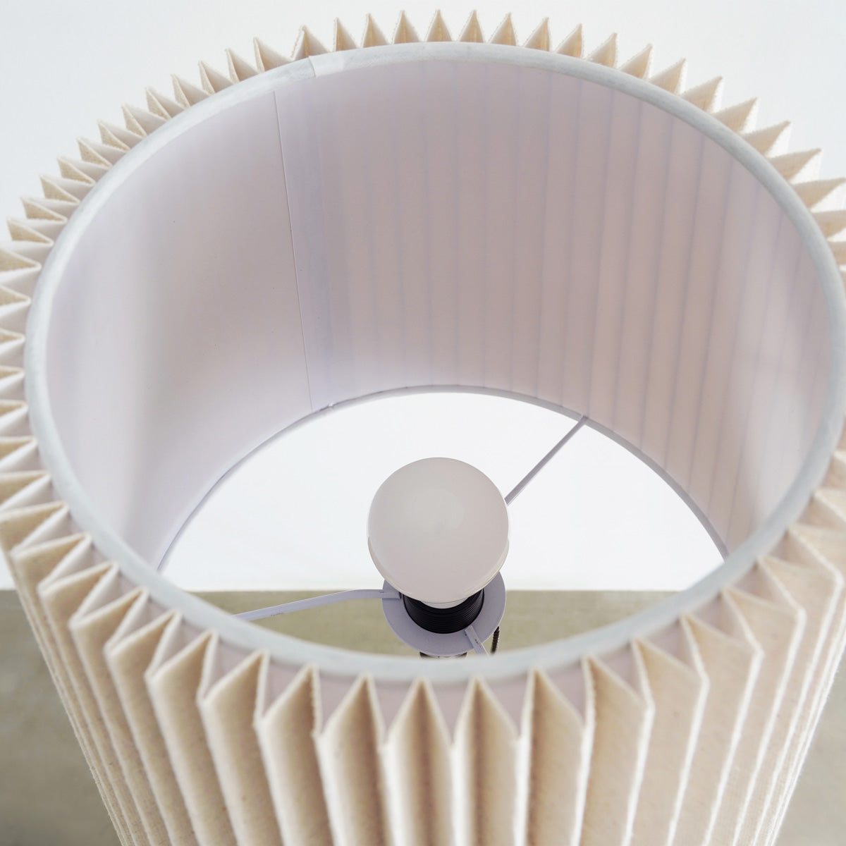 プリーツ状のファブリックのシェードが柔らかな明かりを灯すフロアランプ（電球部分）