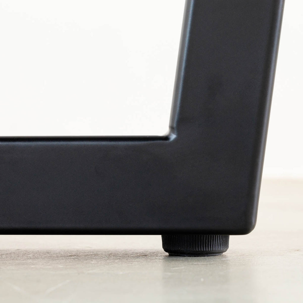 KANADEMONOのホワイトオーク突板天板とマットブラックのトラペゾイド鉄脚を組み合わせたシンプルモダンなテーブル（アジャスター部分）