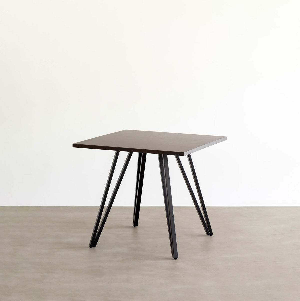 KANADEMONOのラバーウッド・ブラックブラウンのスクエア天板と三角のチューブが華やかなアイアン脚を組み合わせたカフェテーブル（斜め）