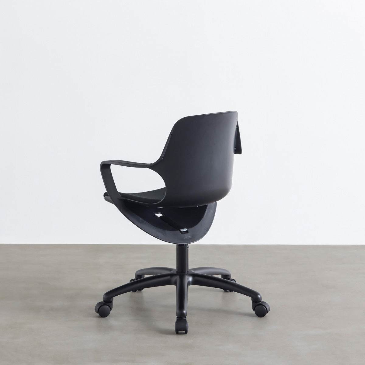 KANADEMONOの背もたれから座面までのなめらかなシルエットが特徴的なオールブラックの回転式デスクチェア(背面)