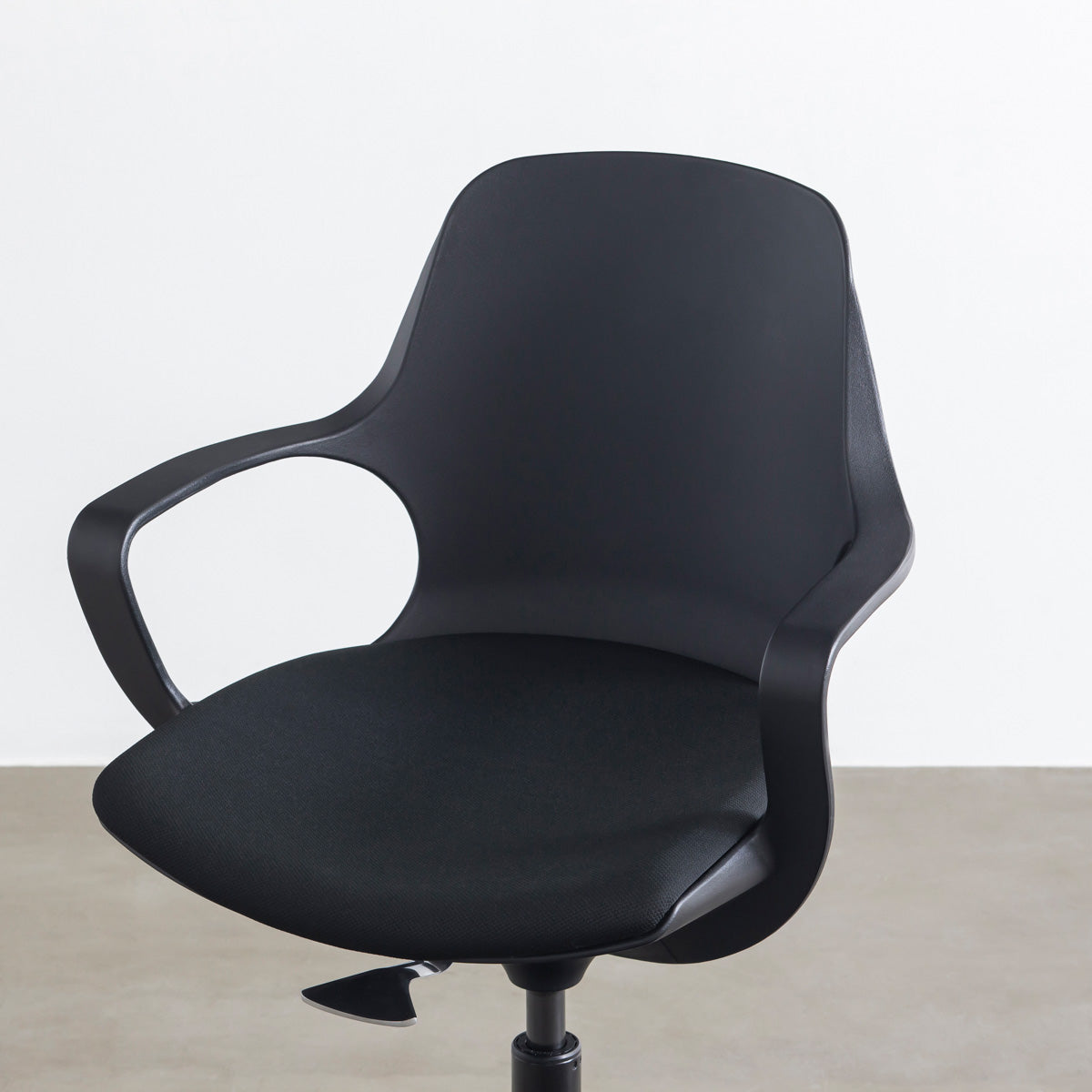 KANADEMONOの背もたれから座面までのなめらかなシルエットが特徴的なオールブラックの回転式デスクチェア(斜め近影)