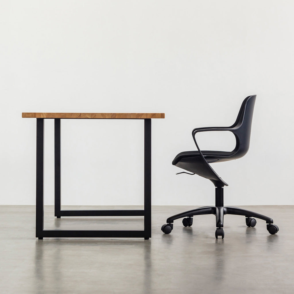 KANADEMONOの背もたれから座面までのなめらかなシルエットが特徴的なオールブラックの回転式デスクチェアの使用例（最大降下時)